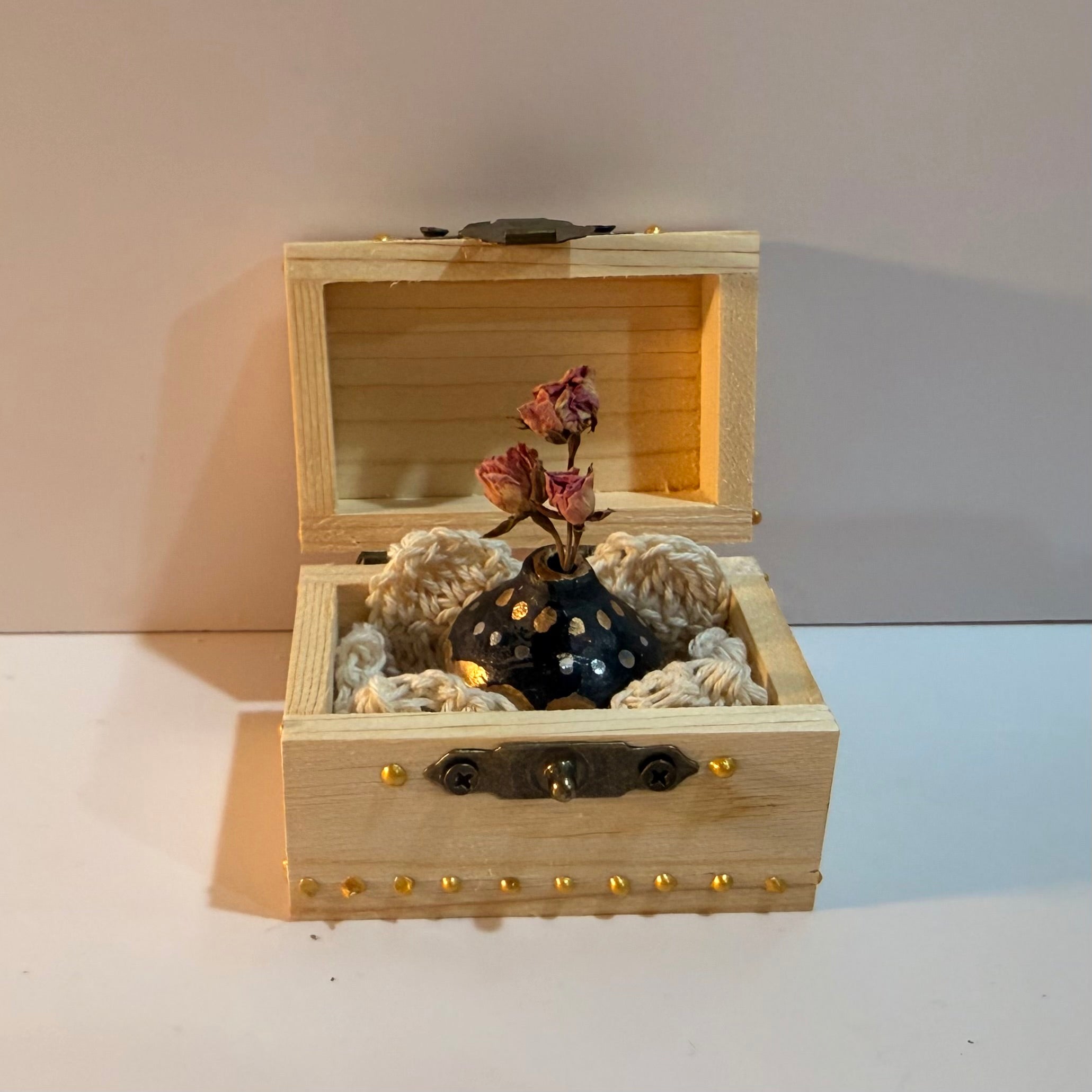 Single miniature vase nestled in a decorated wooden trunk.
